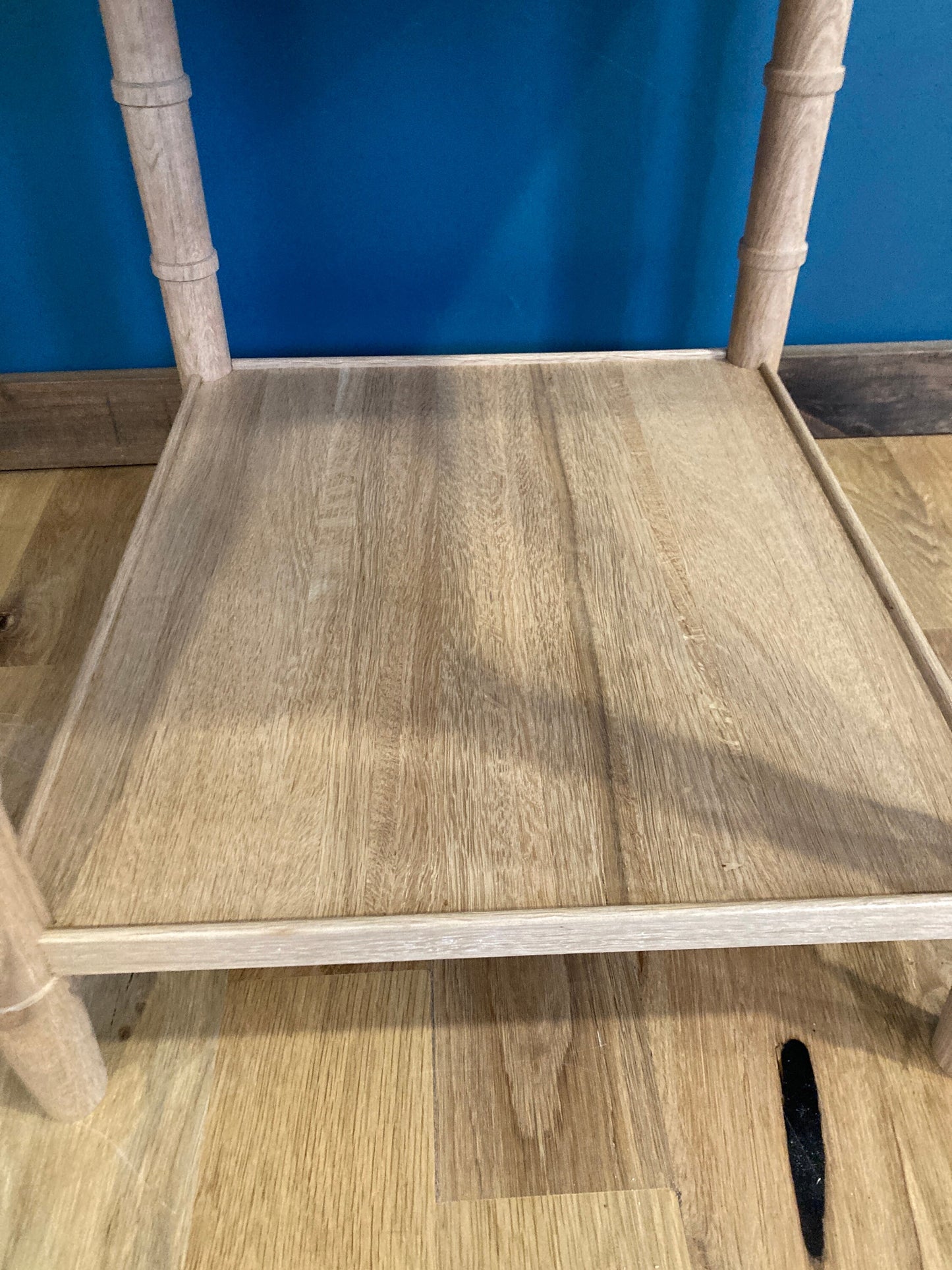 A light wood end table with a rectangular top and a lower shelf. The table has a simple design with four faux bamboo legs and a light wood finish.