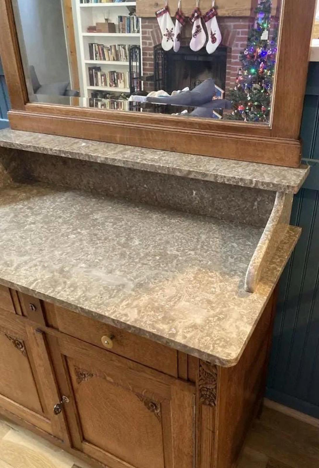 A wooden sideboard with a marble top and two doors. The sideboard has small drawers with a brass knobs.