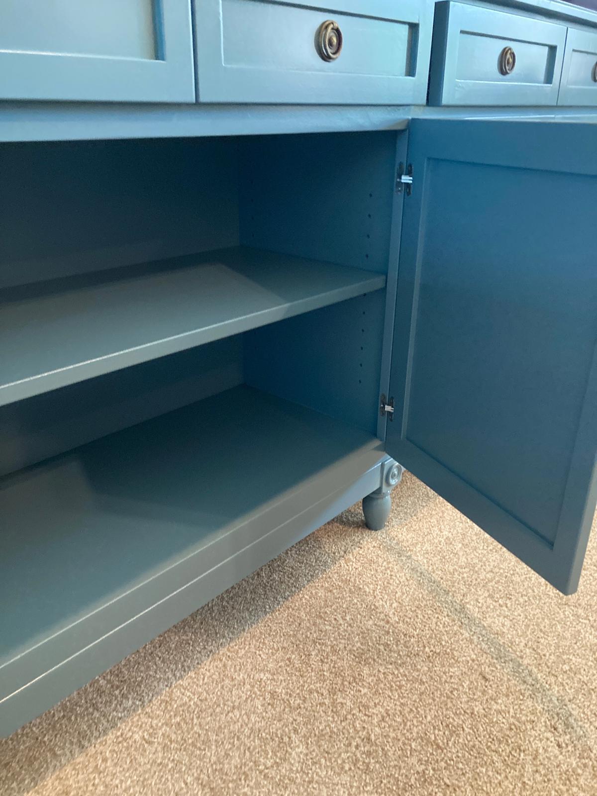 A blue cabinet with drawers and doors. The doors are open and reveal two shelves. The cabinet is sitting on a light brown carpet.