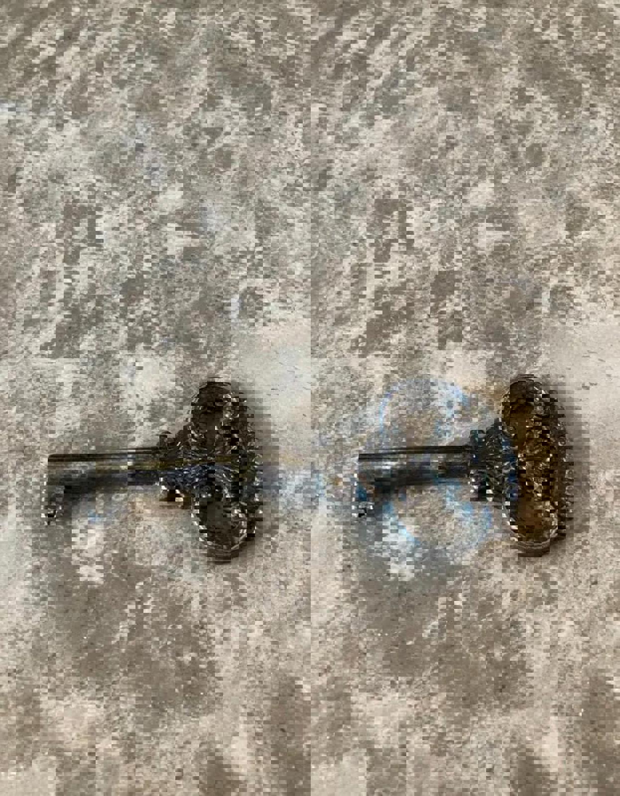 A silver key with an ornate design on the head. The key has a simple, straight shaft. It is used to lock the doors of the cabinet.