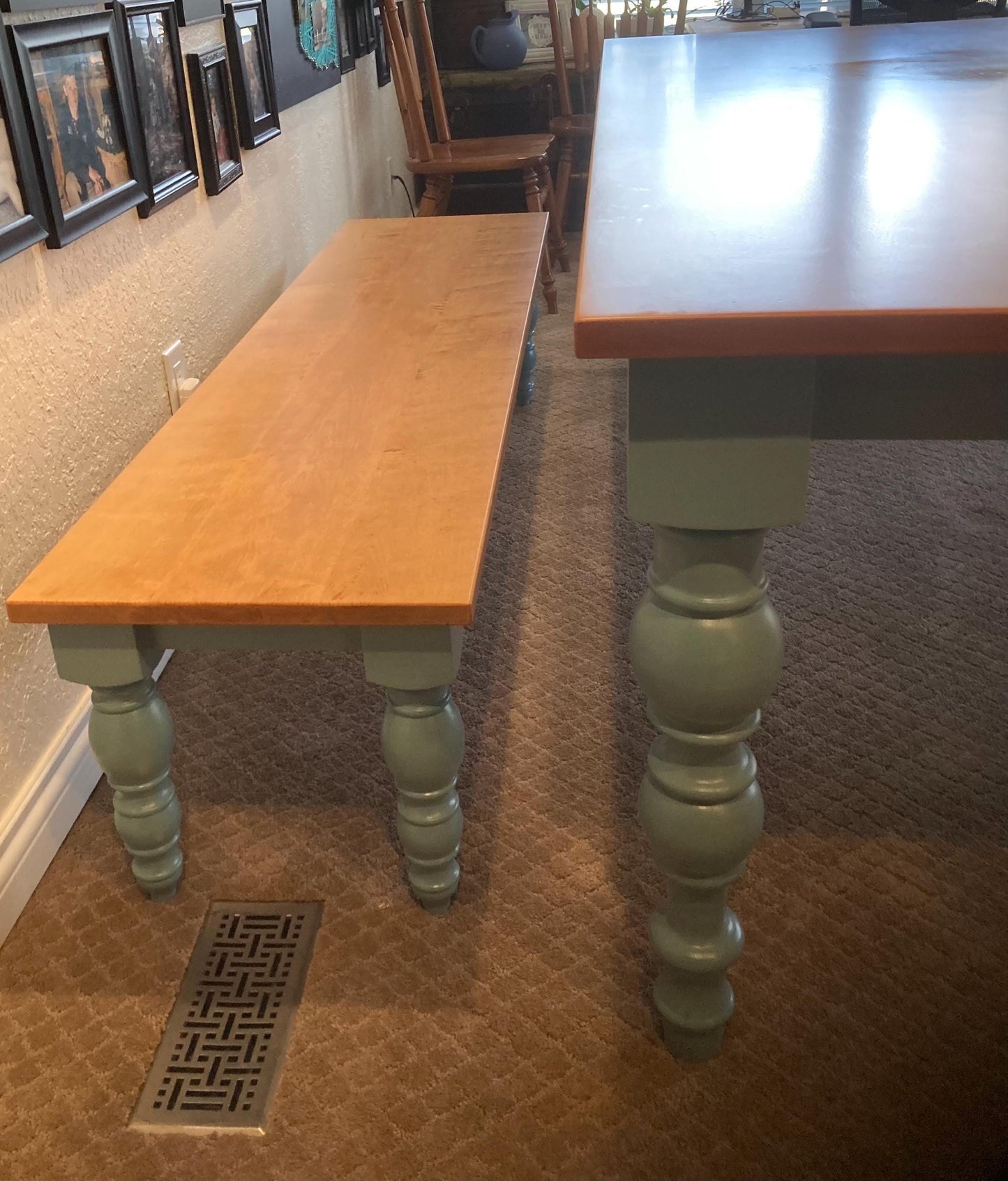 A light wood bench with turned legs and a light blue table with turned legs. The table and bench are on a carpet floor.