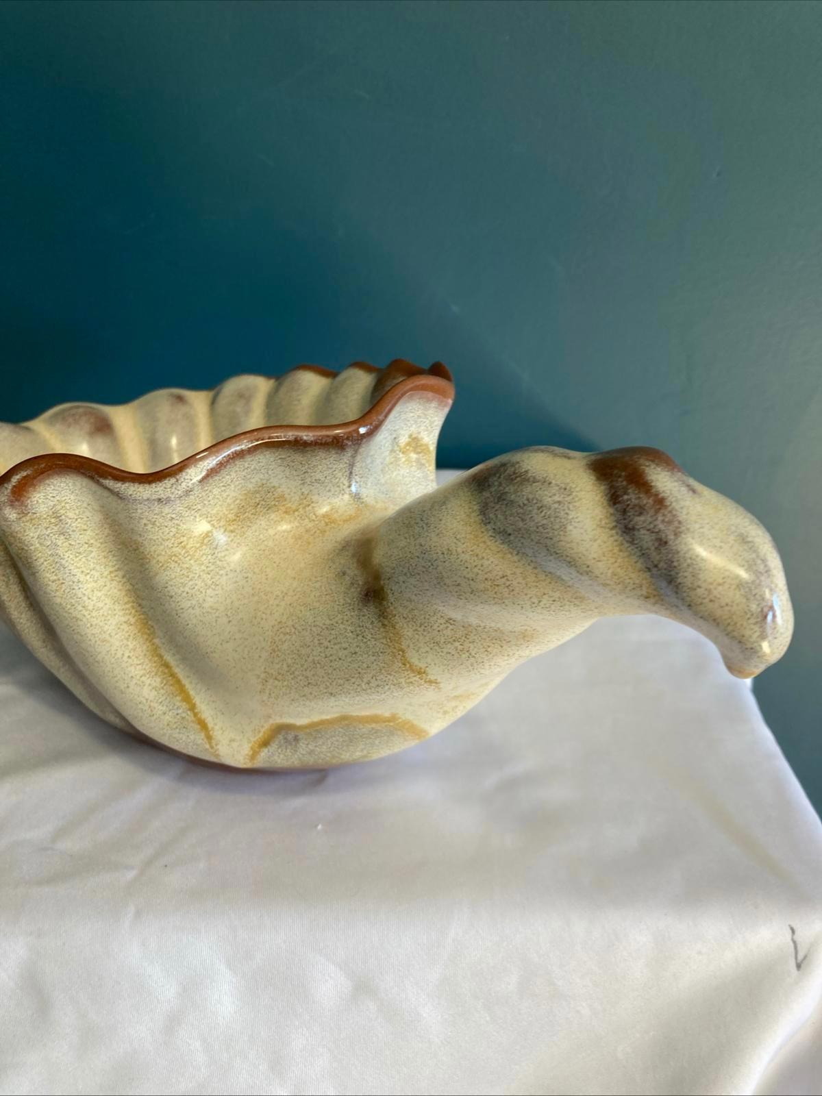 Handmade ceramic bowl with rippled shell-like body and curled handle, glazed in cream and brown tones