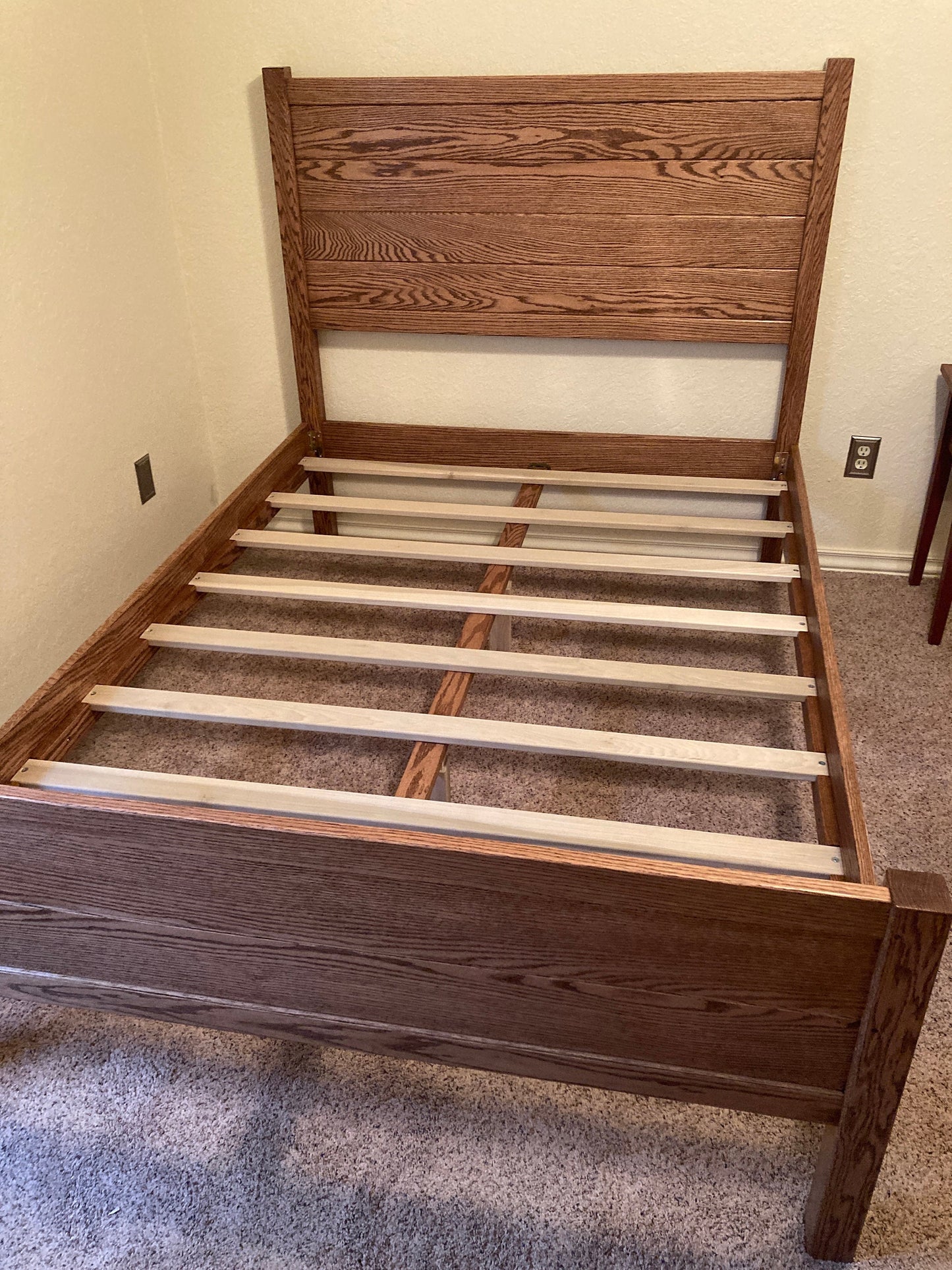 A brown wooden bed frame with a slatted headboard and a slatted base. The bed frame is empty and has no mattress or bedding.