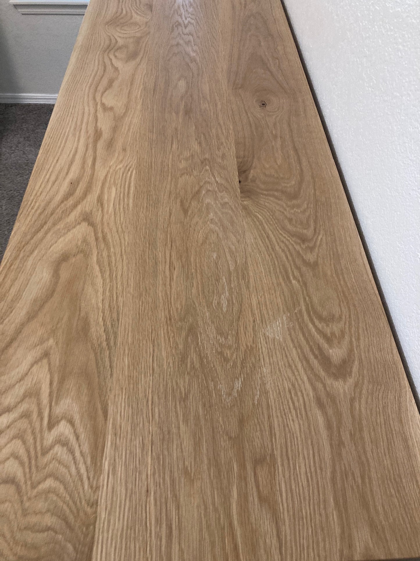 A close-up of a light brown wood surface with a natural wood grain pattern. The surface is smooth and is the dresser top.