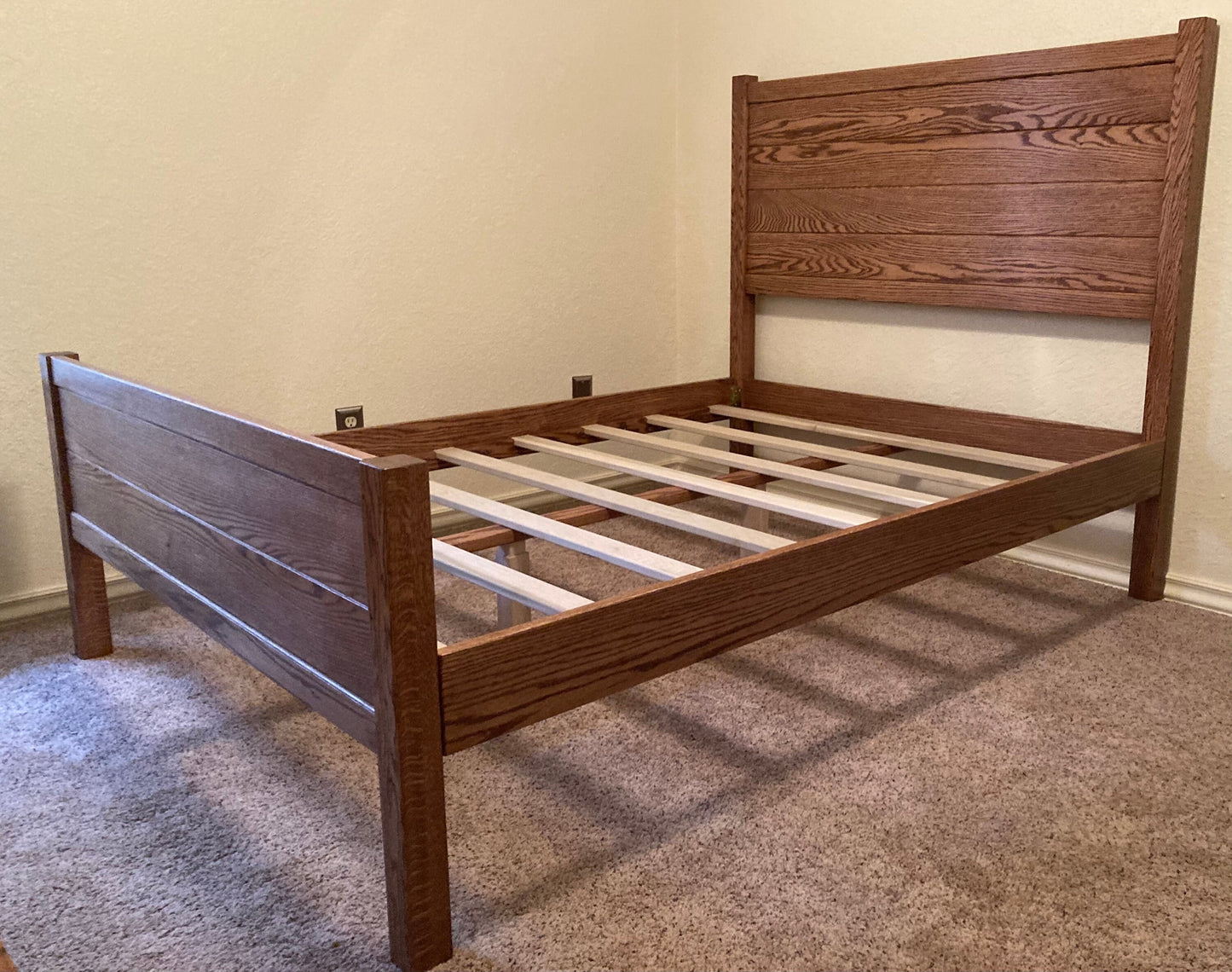 A brown wooden bed frame with a slatted headboard and footboard. The bed frame has a poplar wood slatted support system.
