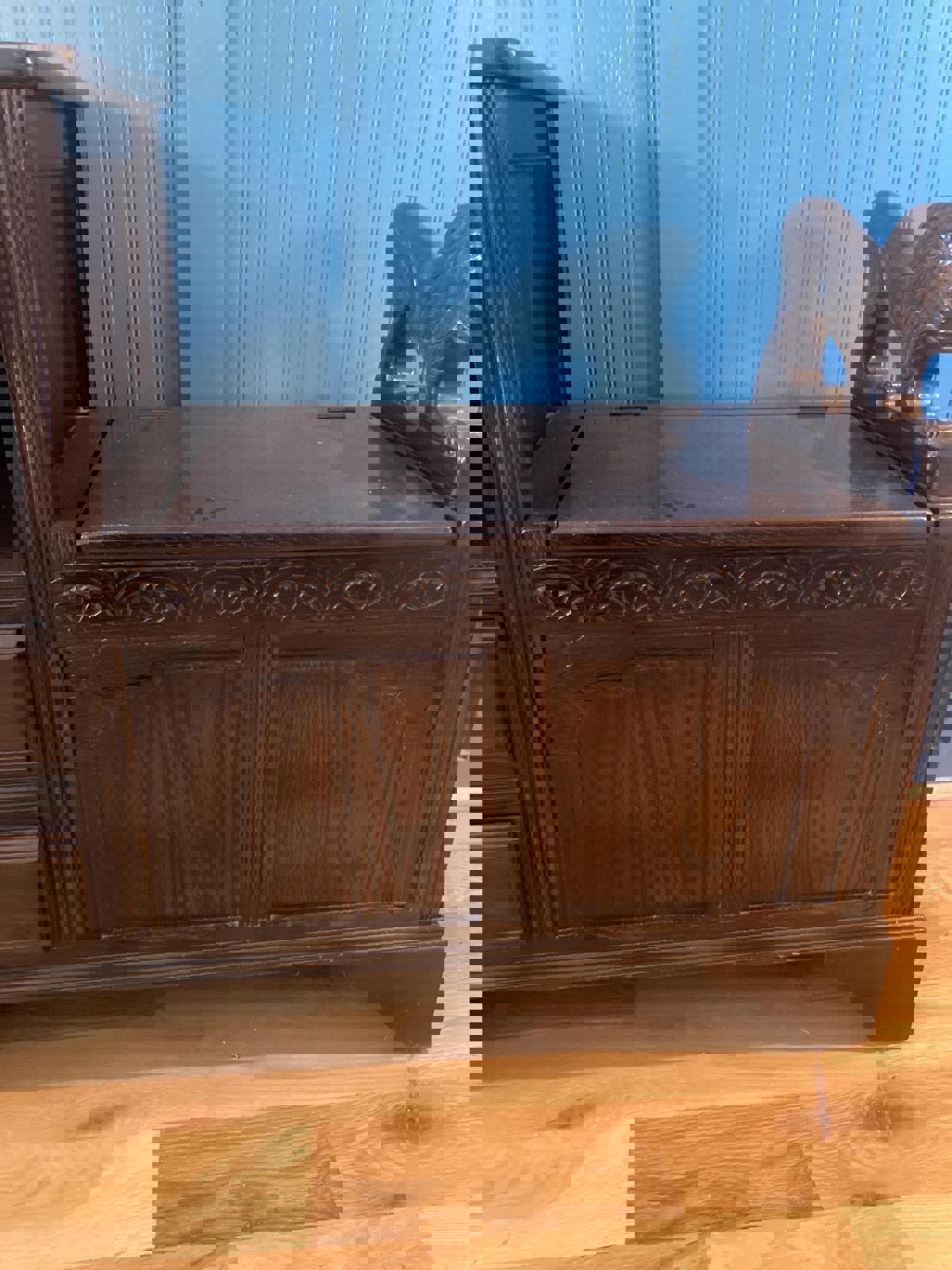 Dark brown wooden storage bench with carved details and lion head armrest. The bench features a hinged top revealing storage space, and is constructed from rich, dark wood. The piece exhibits intricate carvings along the front and sides, adding to its antique or vintage aesthetic. It shows signs of age and wear, adding to its character. The bench is a functional and decorative piece suitable for entryways or hallways.