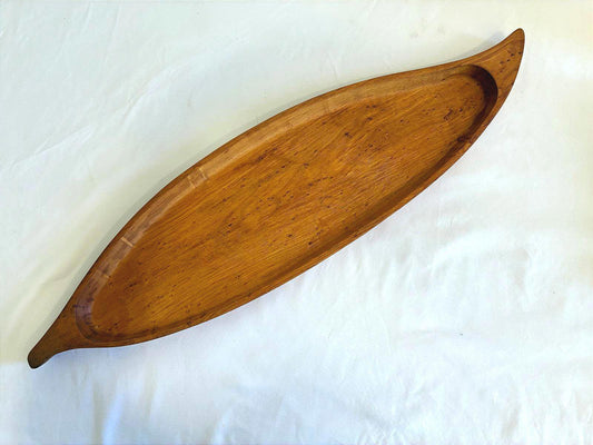 Vintage long Stanwood wooden tray with canoe shape, mid century carved wood serving tray with warm brown finish on white background.
