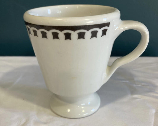 White mug with black decorative pattern on a white surface