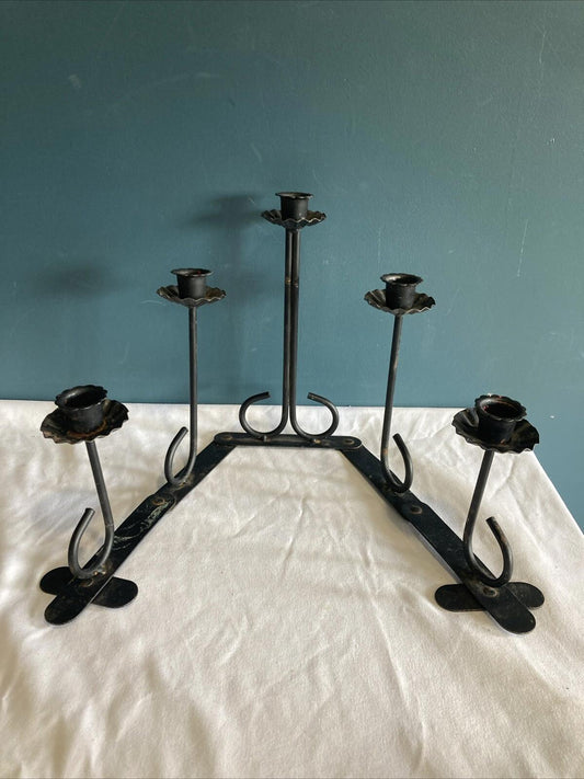 Set of black metal candle holders on a white surface with a blue wall background