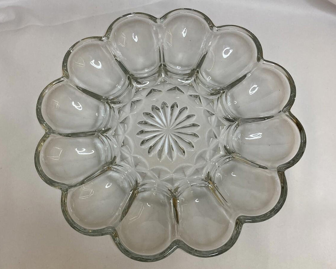 Clear glass egg plate with a decorative center on a white background