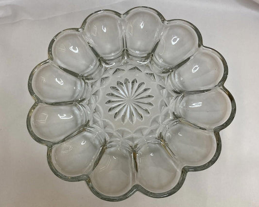 Clear glass egg plate with a decorative center on a white background