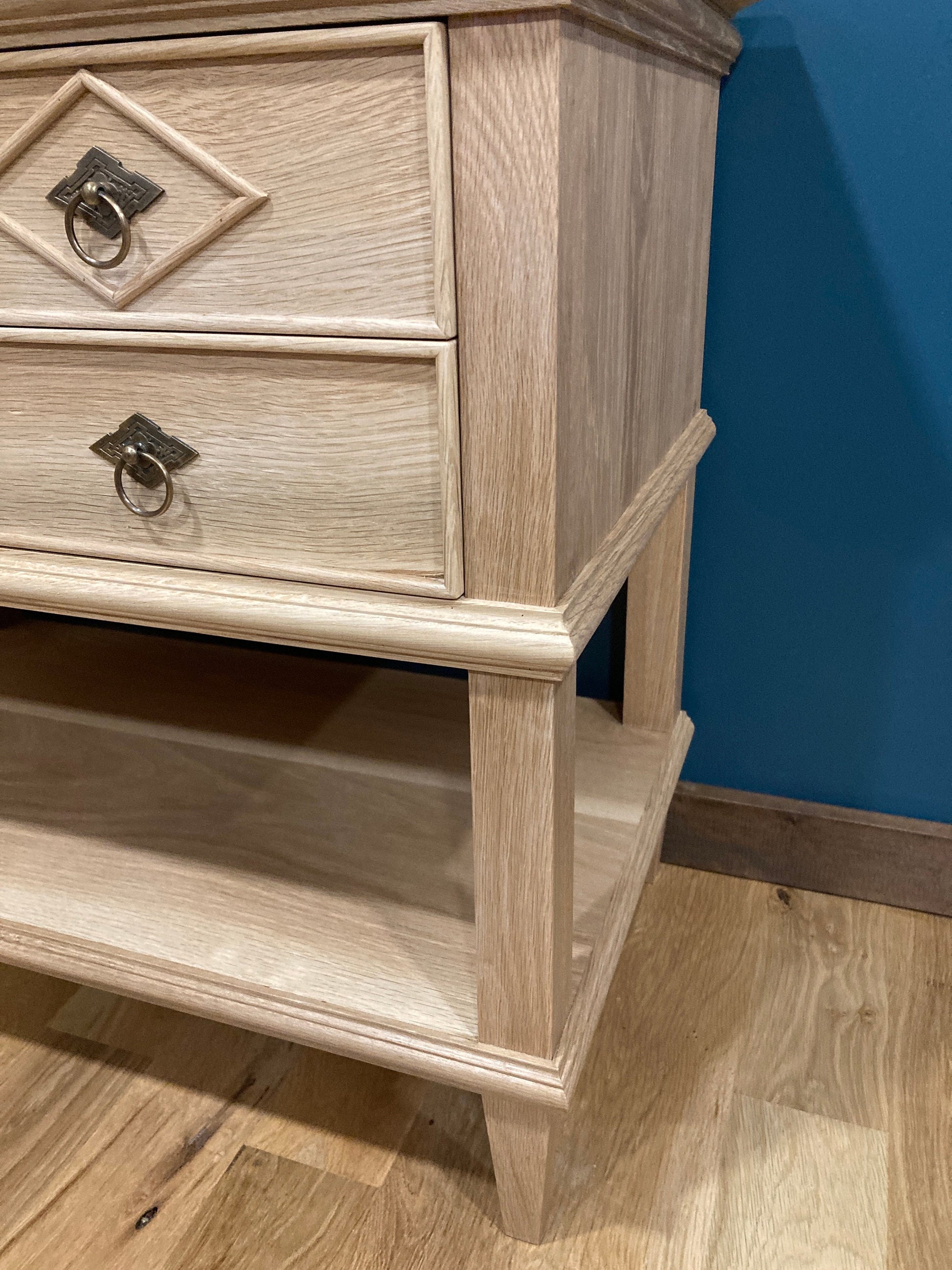 Close up of wood detailing on the leg, shelf, and drawers of the nightstand