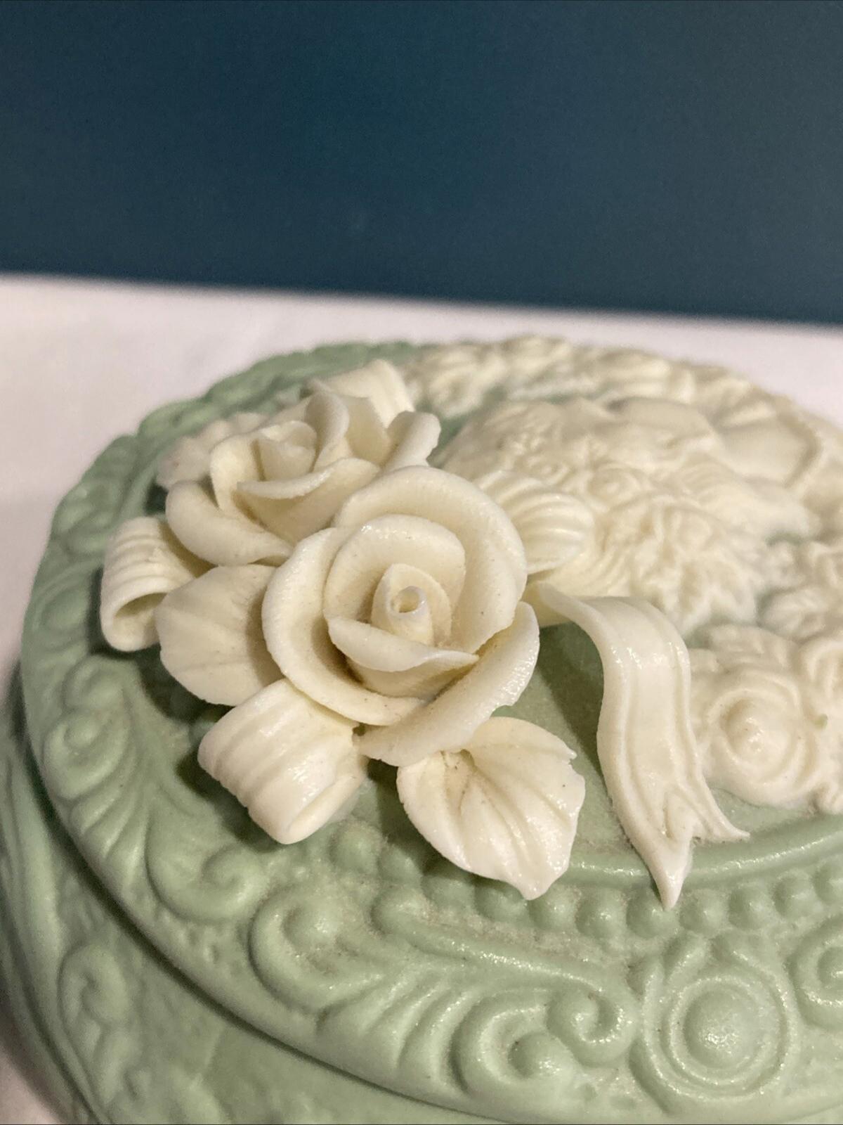 Decorative green box with floral designs on a white surface