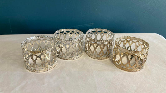 Four silver napkin holders on a white surface with a blue background