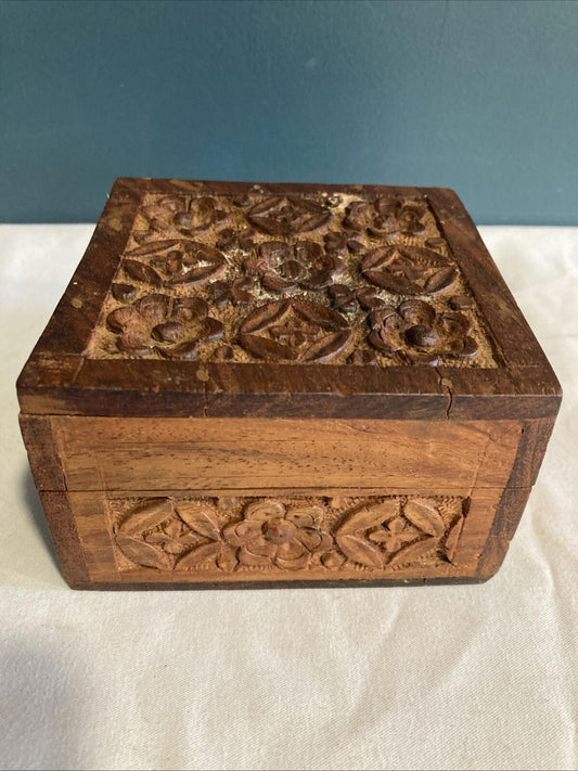 A small vintage carved wood trinket box made in India, with intricate detailing 