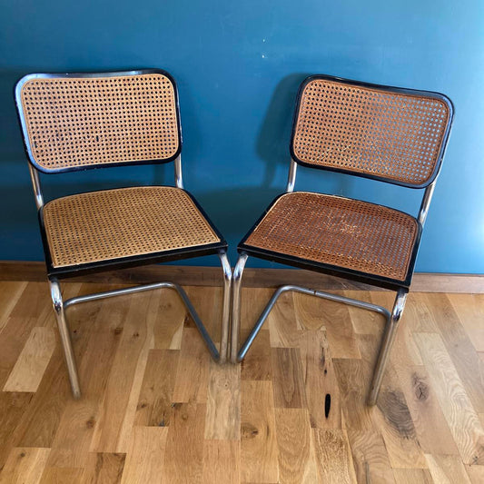 Two wicker chairs with metal frames on a wooden floor.