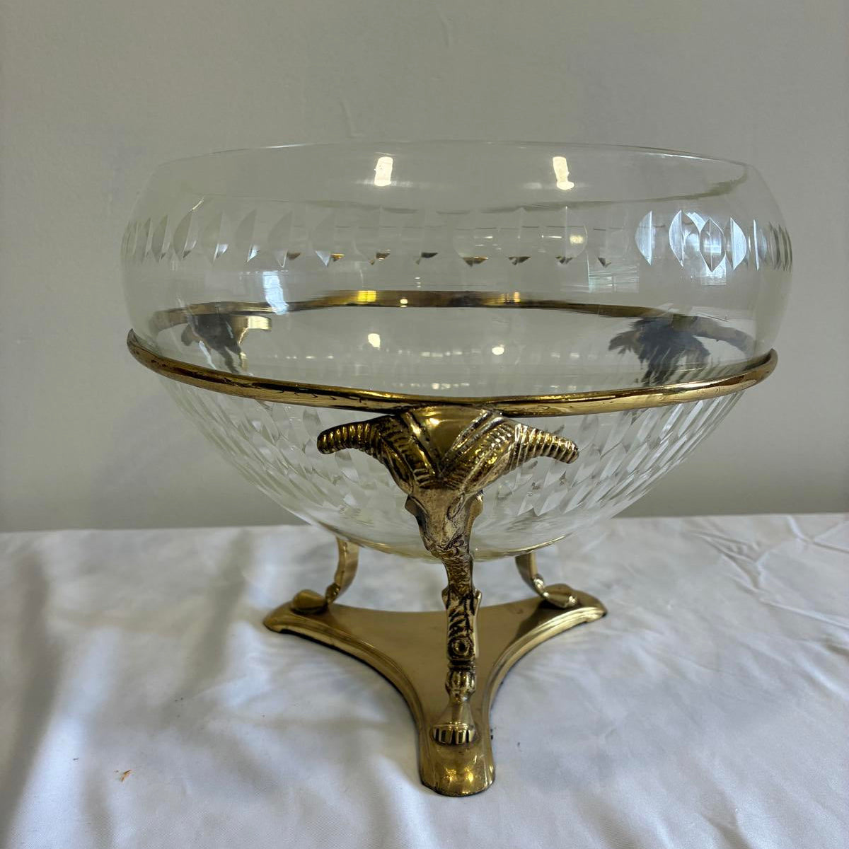 Vintage glass bowl with brass ram head footed base, Hollywood Regency style centerpiece with clear cut glass and gold metal stand.
