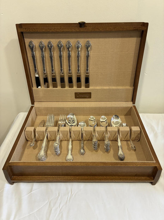 Set of silverware in a wooden case on a white surface