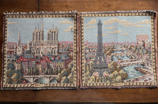 Two tapestries depicting architectural landmarks of Paris on a wooden surface.