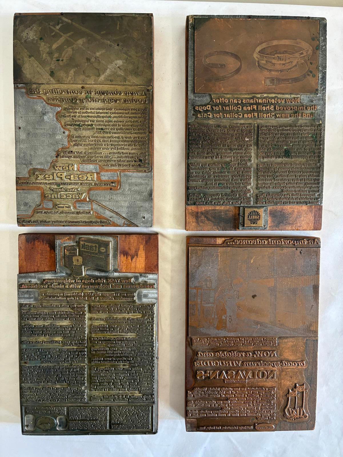 Four vintage metal printing blocks with engraved text and designs on a white background