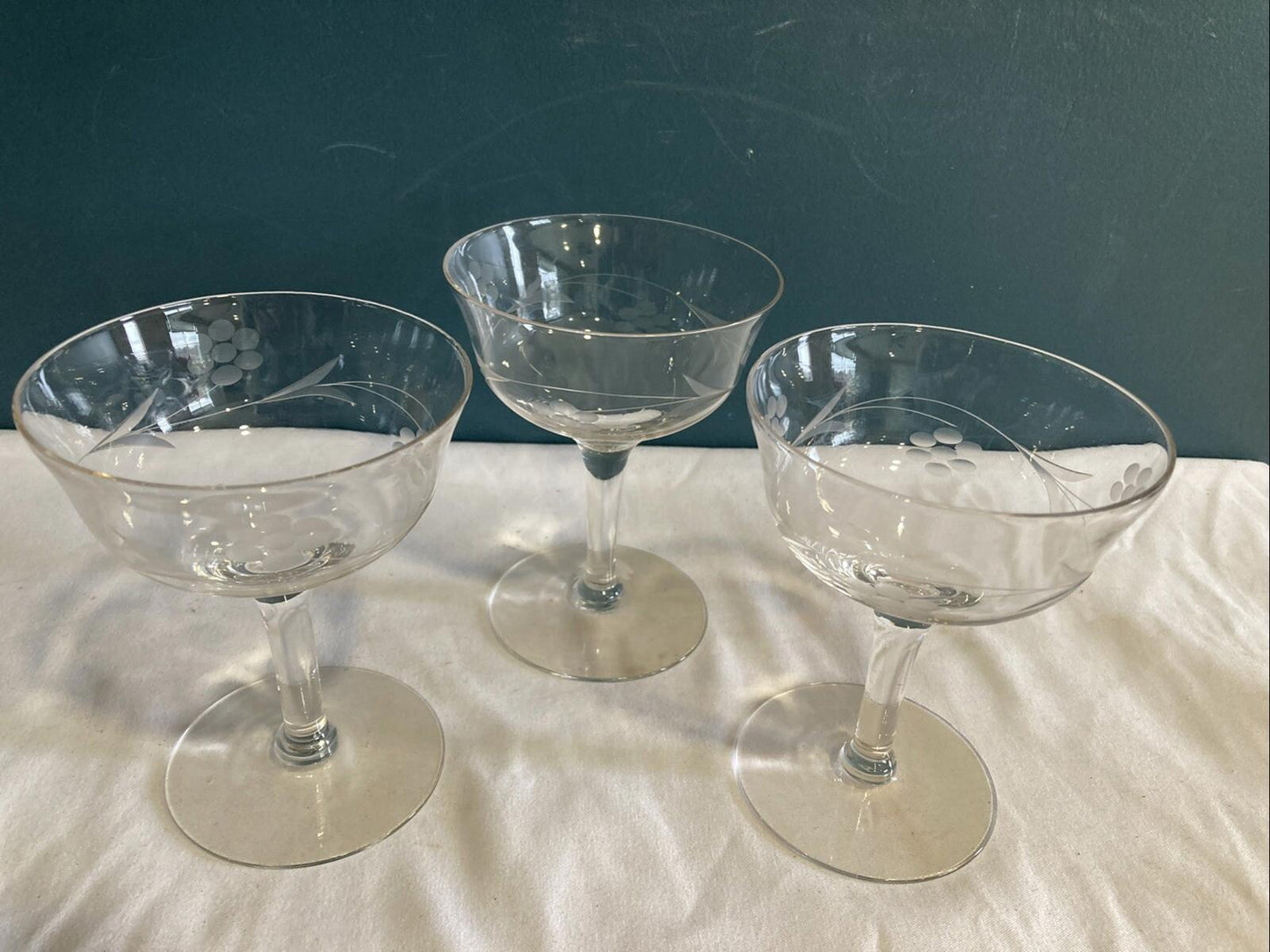 Three clear glass cocktail glasses on a white surface with a dark background