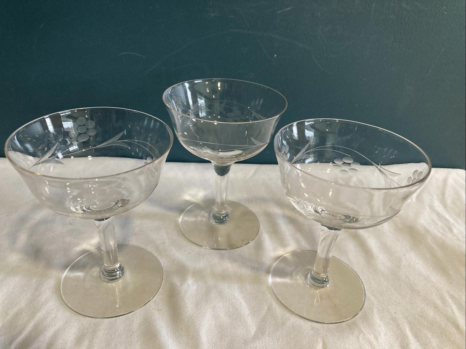 Three clear glass cocktail glasses on a white surface with a dark background