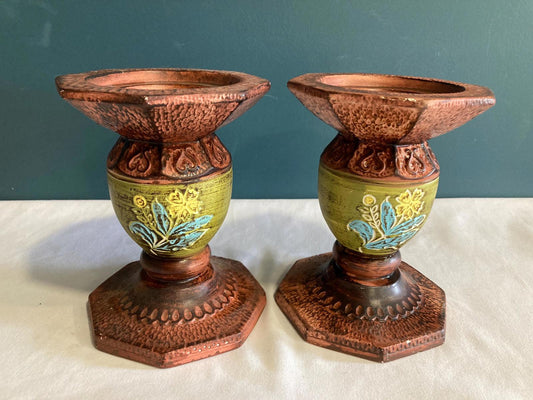 Pair of hand-painted vintage ceramic candleholders in brown with green centers and floral accents on two sides.