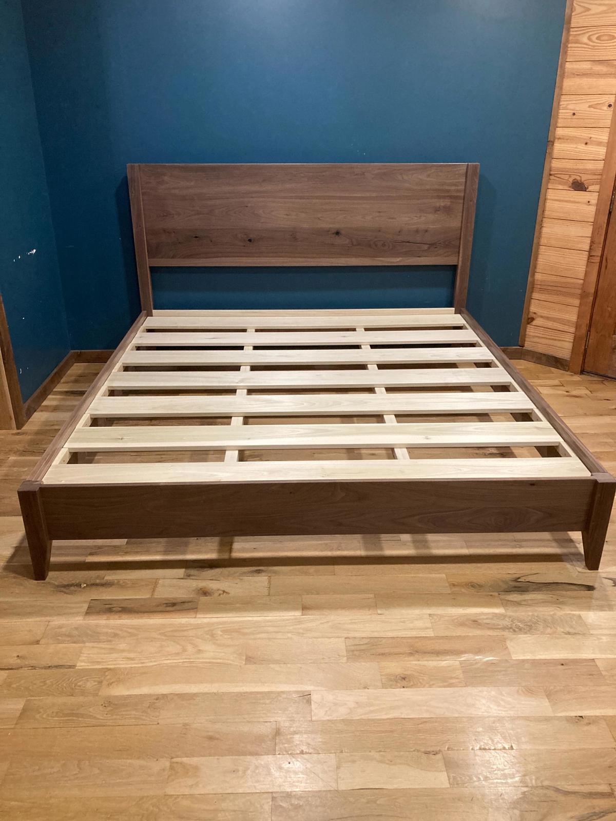 Wooden bed frame against a blue wall