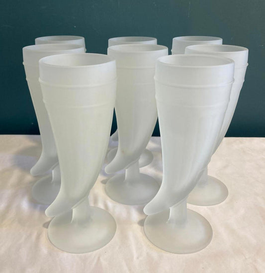 Set of frosted glass goblets on a white surface with a dark background