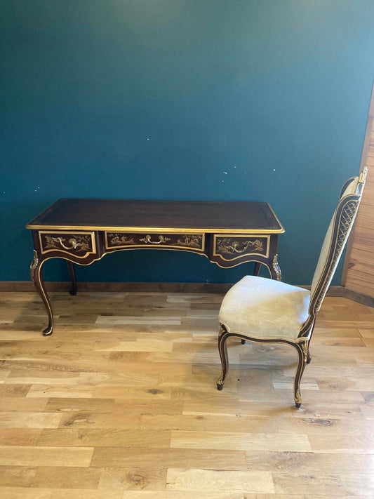 Decorative chinoiserie desk with intricate designs on a wooden floor against a blue wall