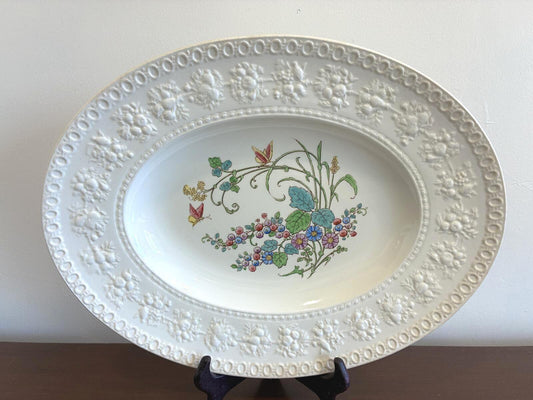 Decorative white plate with floral design on a plain background. made in England by Wedgwood