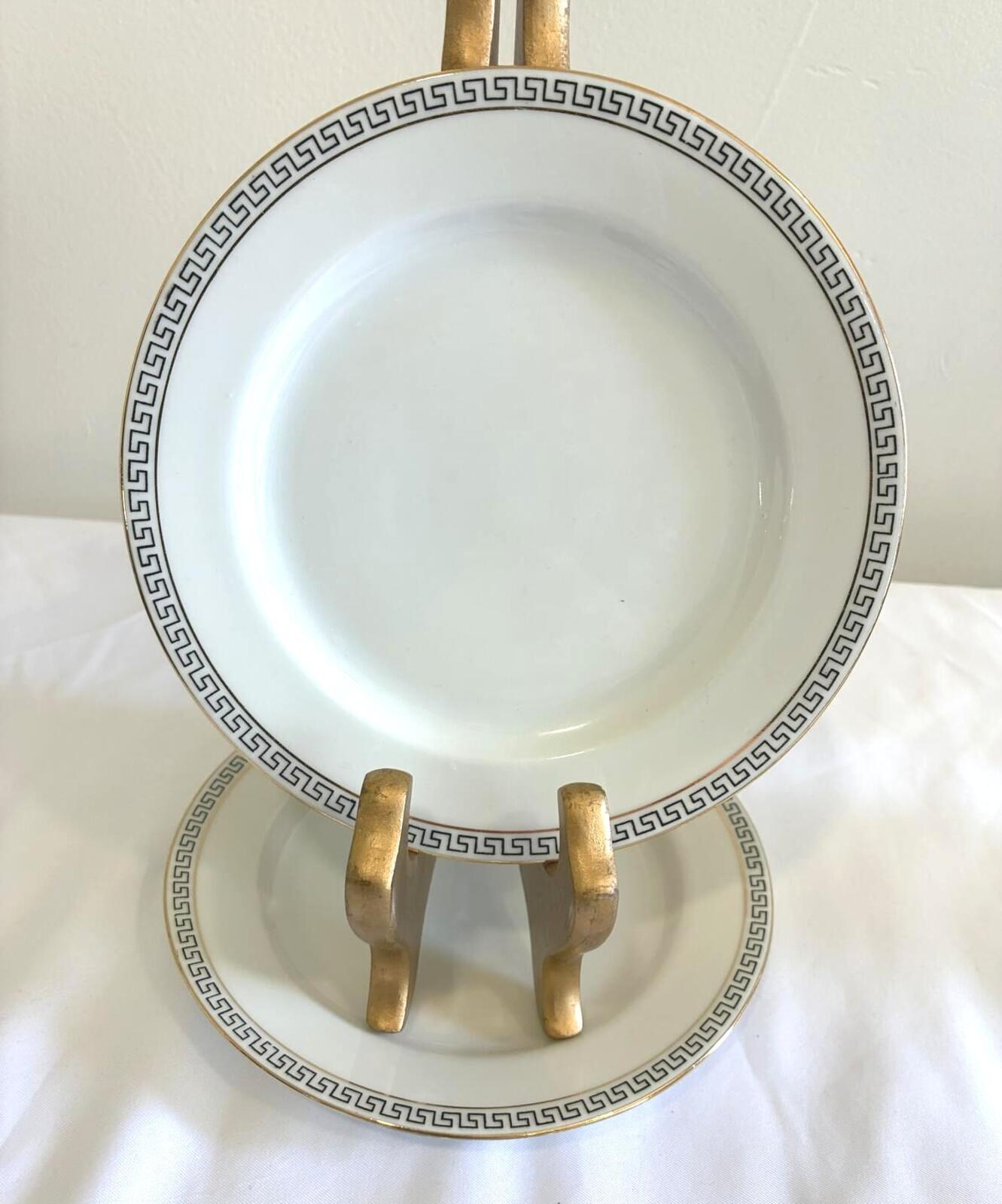 Decorative plate with gold and black detailing on a stand against a white background