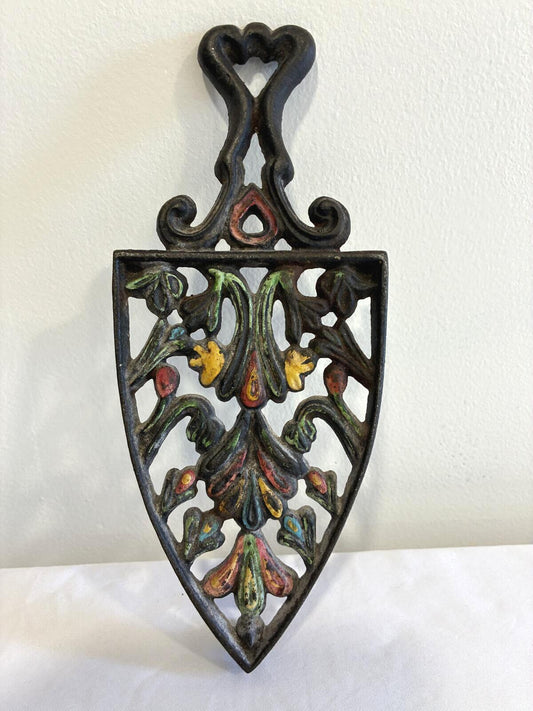 Vintage Wilton cast iron floral wall trivet with hand-painted red, yellow, green, and blue accents and ornate openwork design.