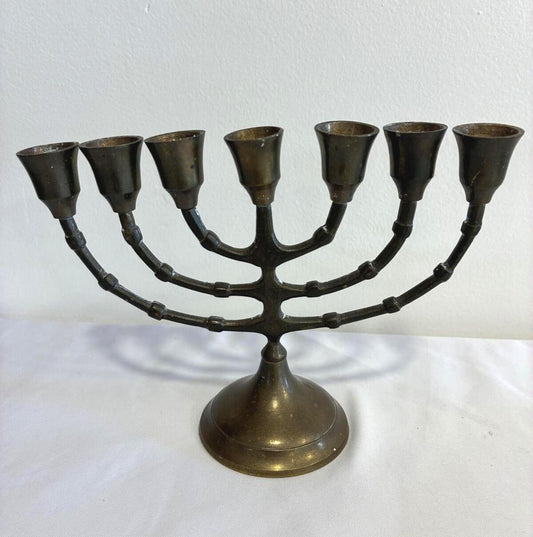 Vintage solid brass seven-branch menorah with bamboo-style arms and aged patina displayed against a neutral background.